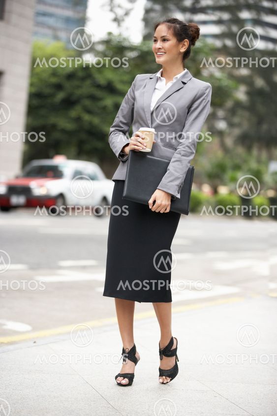 Businesswoman Walking Along Street Holding Takeaway Coffee