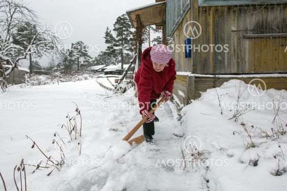 Elderly woman cleans the snow shovel near his home in the...