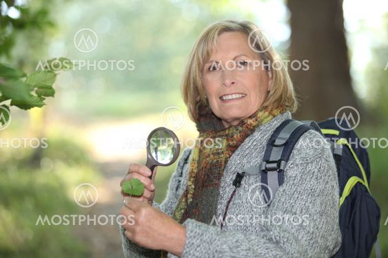 Woman examining leaf with magnifying glass