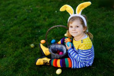 Cute little toddler girl sitting on green grass and wear...