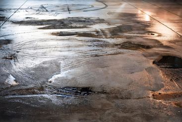 Wet concrete reflecting the evening light, showing tire...