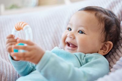 Happy baby, rattle and child in bedroom for childhood...