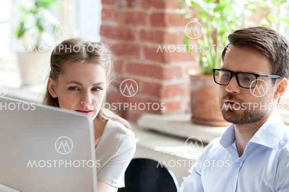 Serious employees work at computer cooperating in office