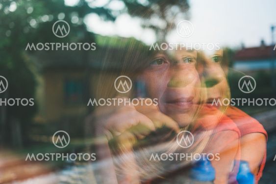 Reflection in the window of a young woman traveling by...