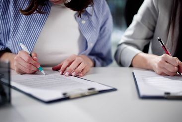 Professional Woman Handing Documents To Colleague
