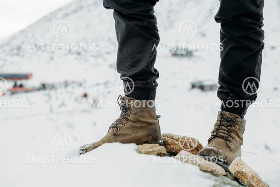 Feet in boots on a background of snowy mountains after a...