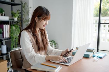 Asian woman using laptop to study student engaged in...
