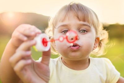 Little girl blowing bubbles in nature