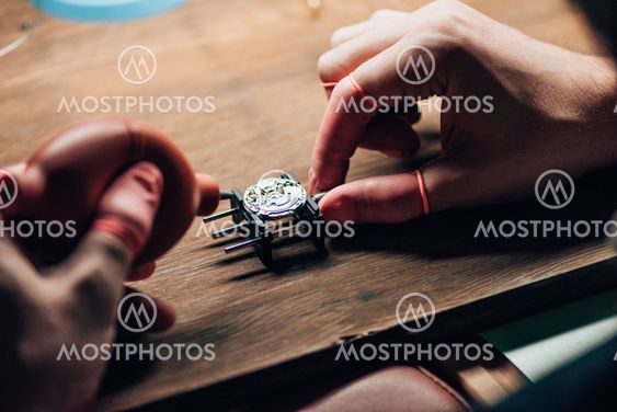 Cropped view of clockmaker using blower for wristwatch...
