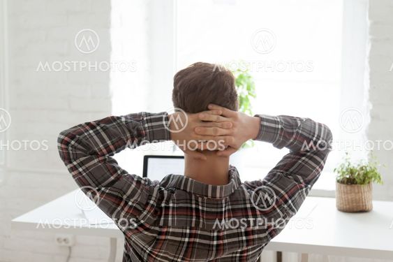 Rear view at relaxed man resting from work on laptop