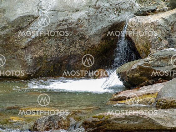 Beautiful small waterfall flows into the forest pond