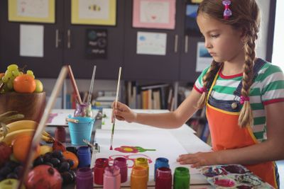 Concentrated girl painting at desk