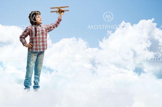 Boy in helmet pilot playing with a toy airplane