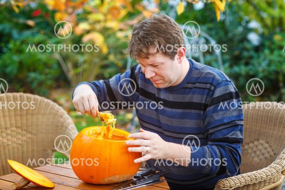 Young man making halloween pumpkin