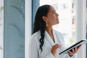 Business woman, tablet and reading in hallway at modern...