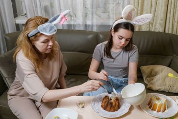 Mother and daughter decorating Easter cakes together.