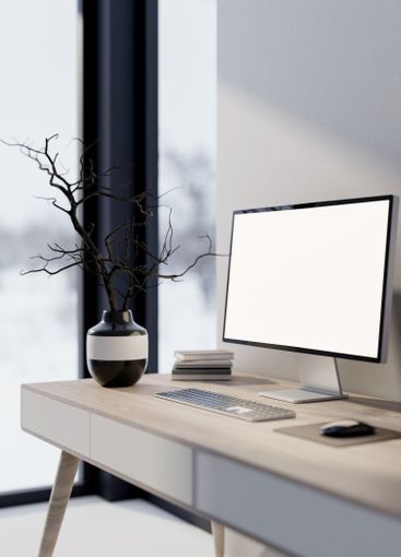 Computer and a black ceramic vase with dried branches...