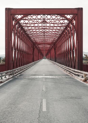 Red truss bridge over a road, supported by metal girders