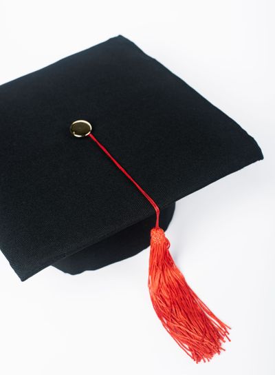 Black graduation cap with red tassel isolated on white