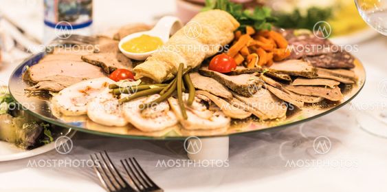 platter of sliced ham,salami and cured meat with vegetable decoration on festive table.