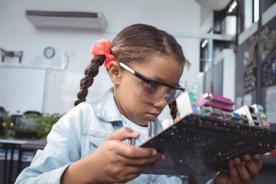 Concentrated elementary student examining circuit board