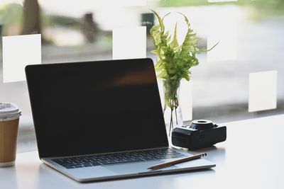 Laptop computer, camera, pencil and coffee on table.