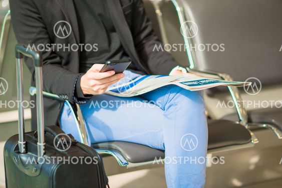 Young caucasian man with newspaper and cellphone at the...