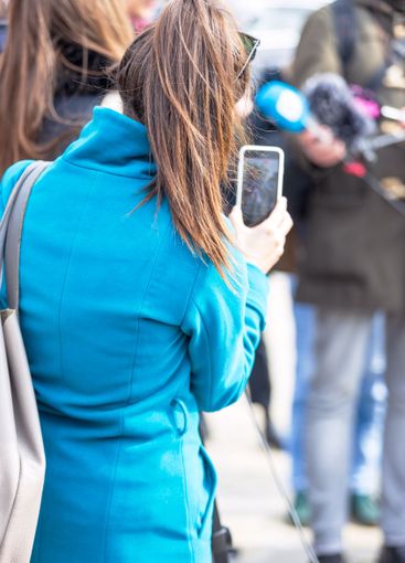Mobile journalist filming media event with a smartphone