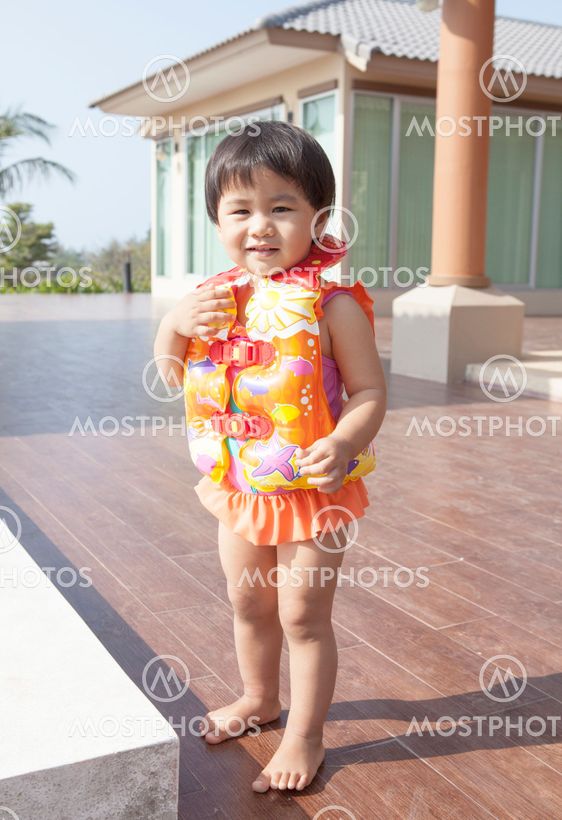 file young kid wearing life jacket vest standing at home terrace and smiling