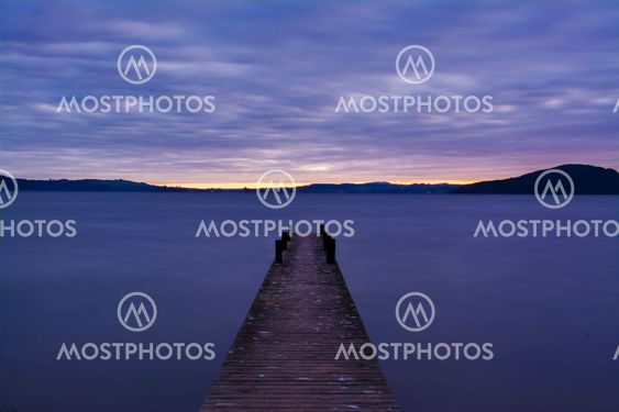 Romantic scene at a pier looking out upon Lake Rotorua at sunrise