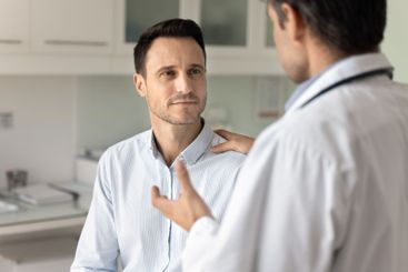 Male clinic patient listening to doctor in hospital office
