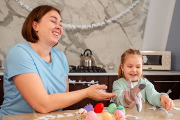 Laughing mother and smiling little girl play together...