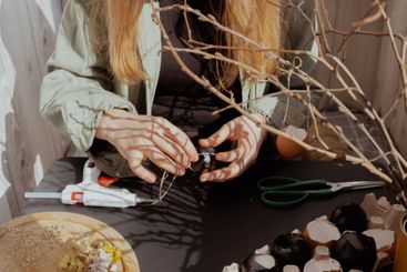 Unrecognizable woman creating Easter holiday decoration...