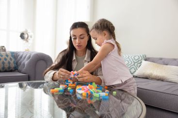 Loving mom and cute toddler daughter playing developing...