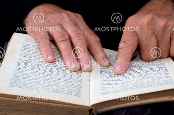 Senior's hands on old book