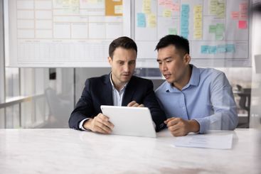 Serious Latin businessman consulting male Asian business...