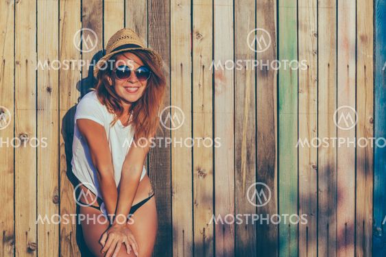 Summertime portrait of young woman by the fence