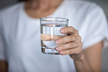 Young woman hold glass drinking pure mineral water