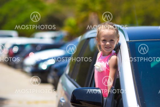 Little adorable girl in the car looking throw window at...