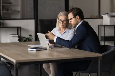 Male female colleagues using modern laptop at workplace