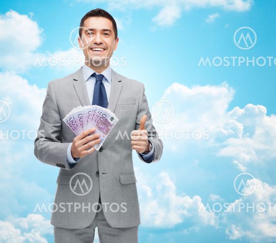 smiling businessman with money showing thumbs up
