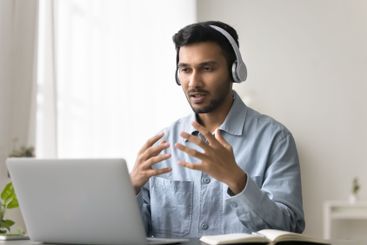 Young male in headset talk by videocall using notebook...