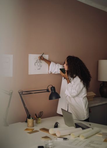 Busy female architect talking through speaker phone while...