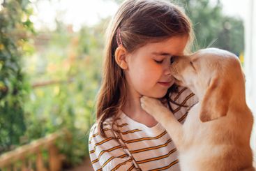 Close-up portrait of a little girl hugging a puppy. A...