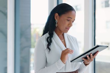 Business woman, tablet and reading in hallway at modern...