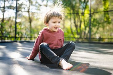 Little boy jumping on a trampoline in a backyard on warm...