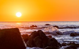 close up shot of waves hitting a stone at the beach at...