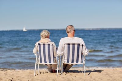 senior couple sitting on chairs at summer beach