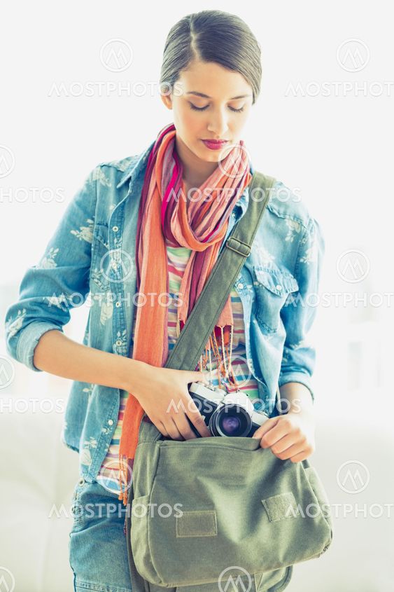 Young pretty woman taking camera from her bag