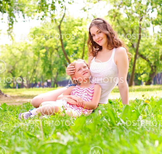 mother and daughter sitting together on the grass